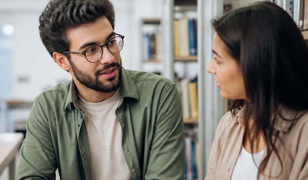 Pessoas conversando de pé junto às estantes antes de o encontro abrir